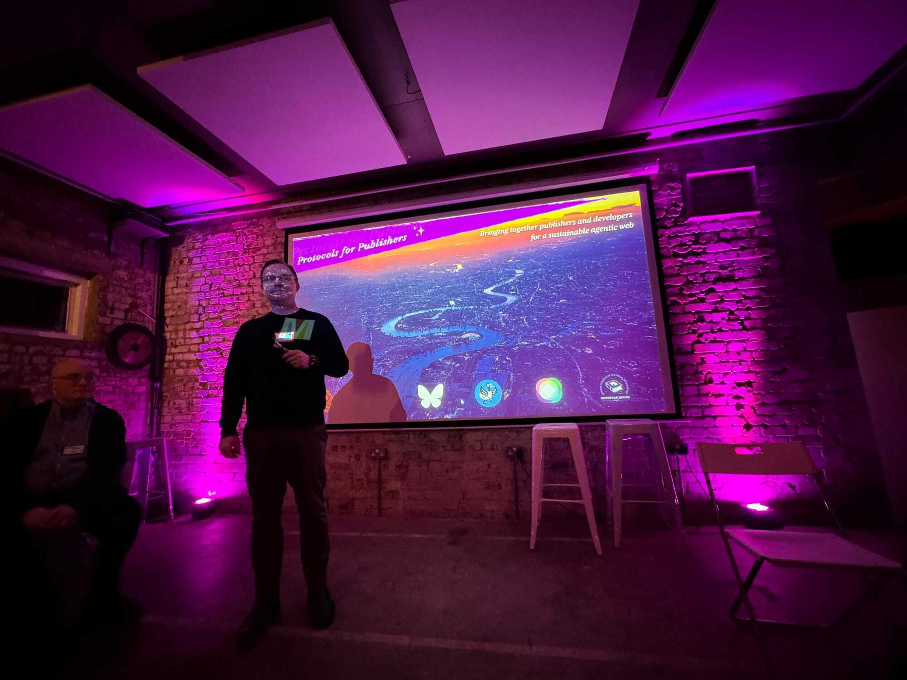 Chad standing in front of a slide presenting in some moody lighting